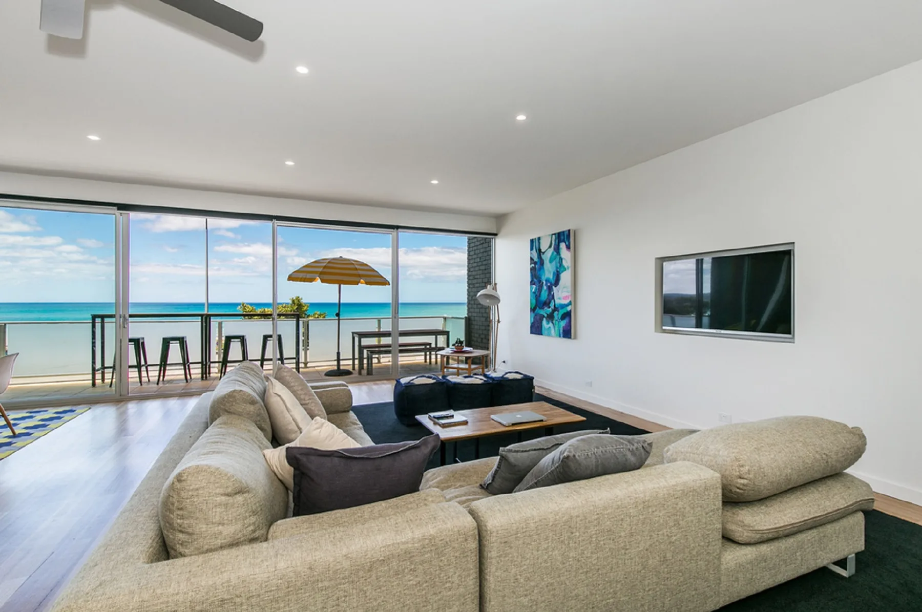 A living room with seating faces large windows overlooking the beach.