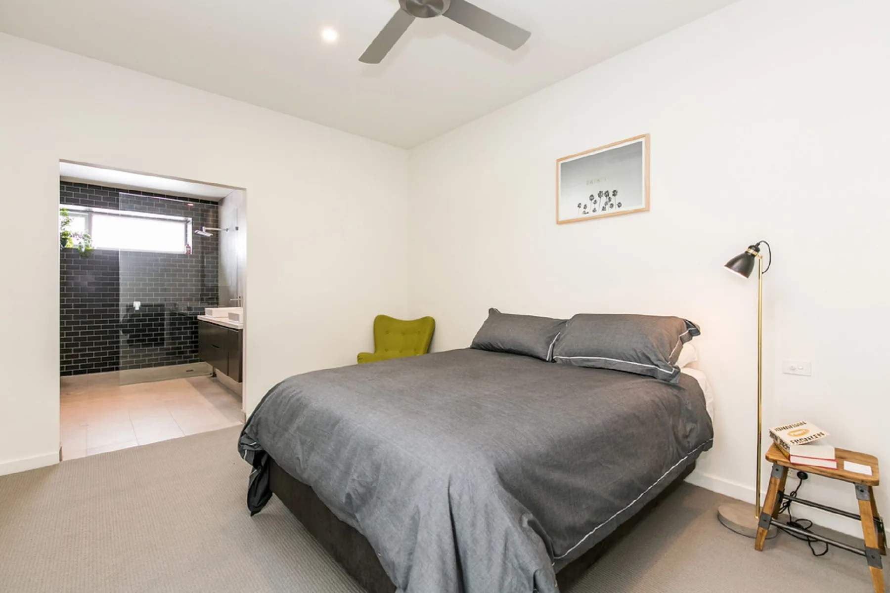 A bedroom with a large bed and an open doorway to a tiled bathroom.