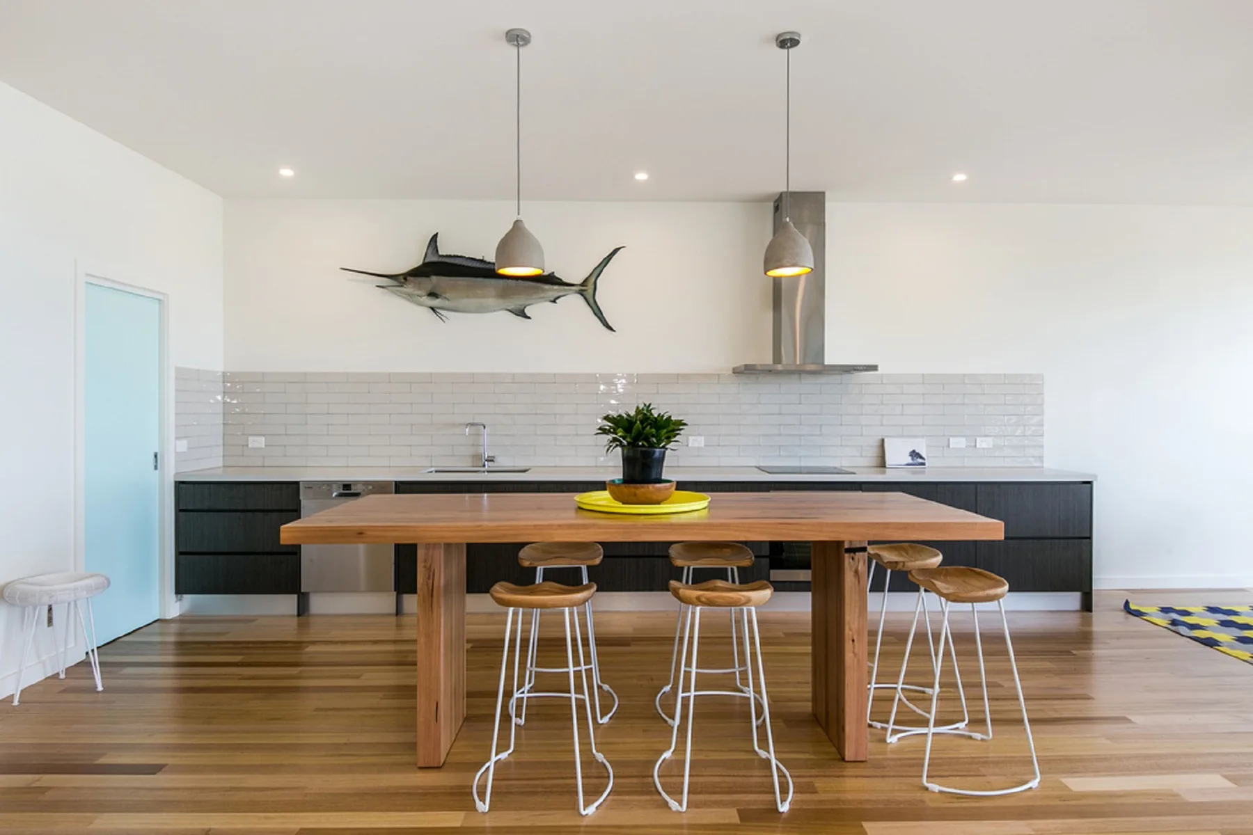 A modern kitchen with a wooden island, bar seating, and pendant lights.
