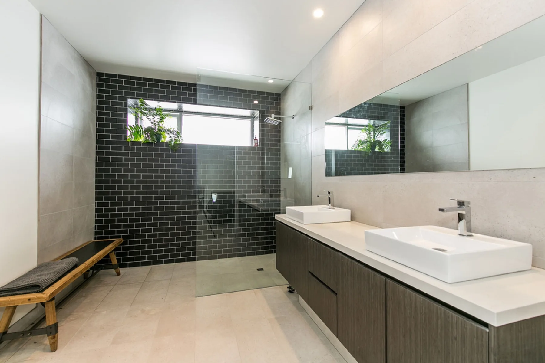 A modern bathroom has a long vanity beside a glass shower.