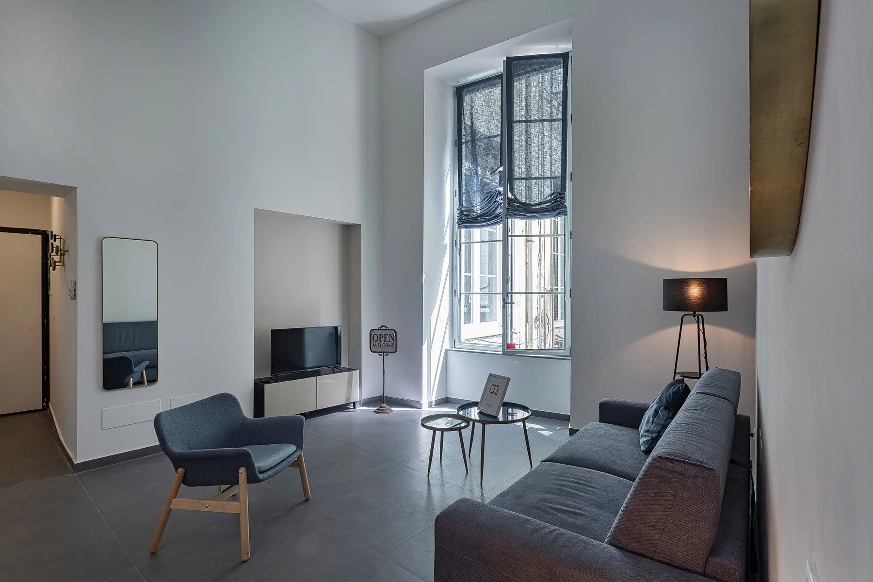 Una sala de estar moderna con asientos alrededor de una mesa baja y una ventana alta.
