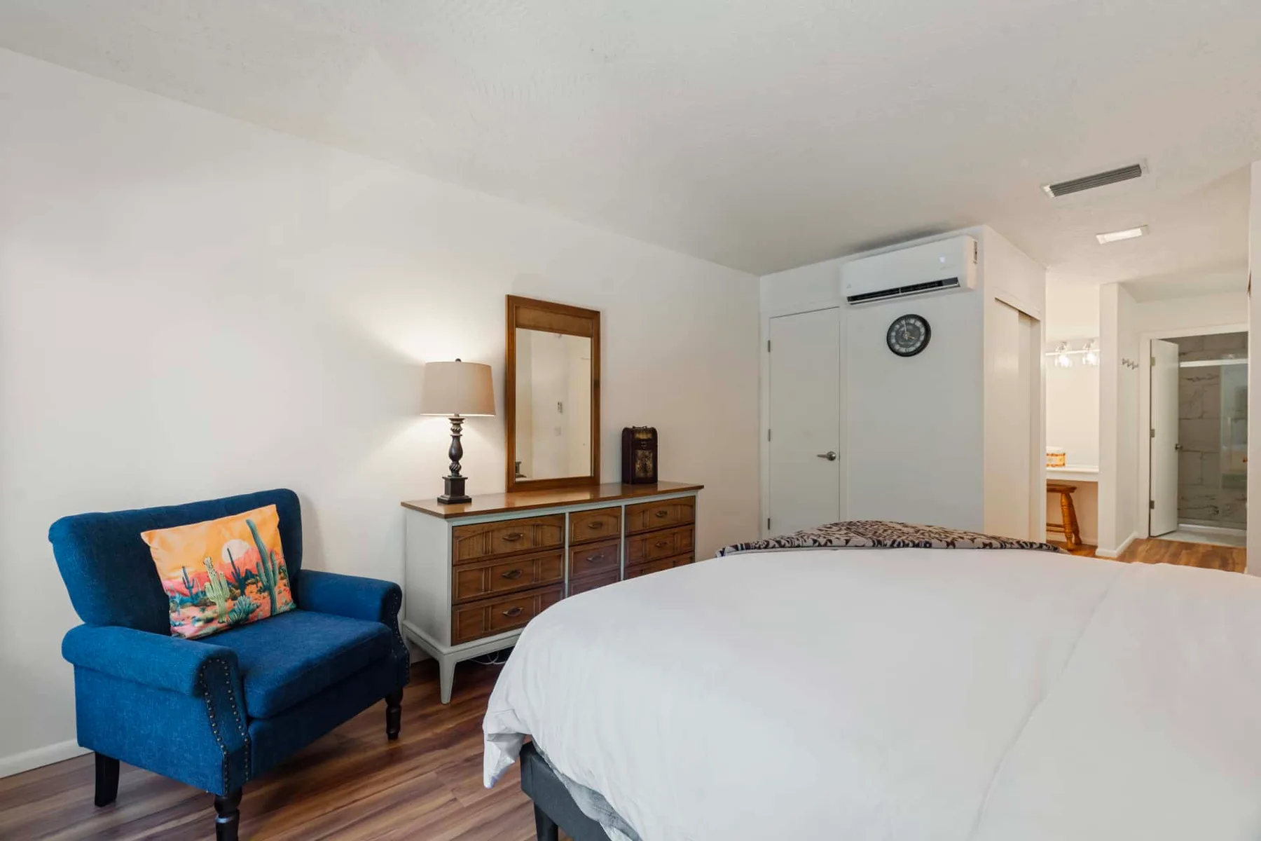 A bedroom with a bed, dresser, and blue upholstered seating.