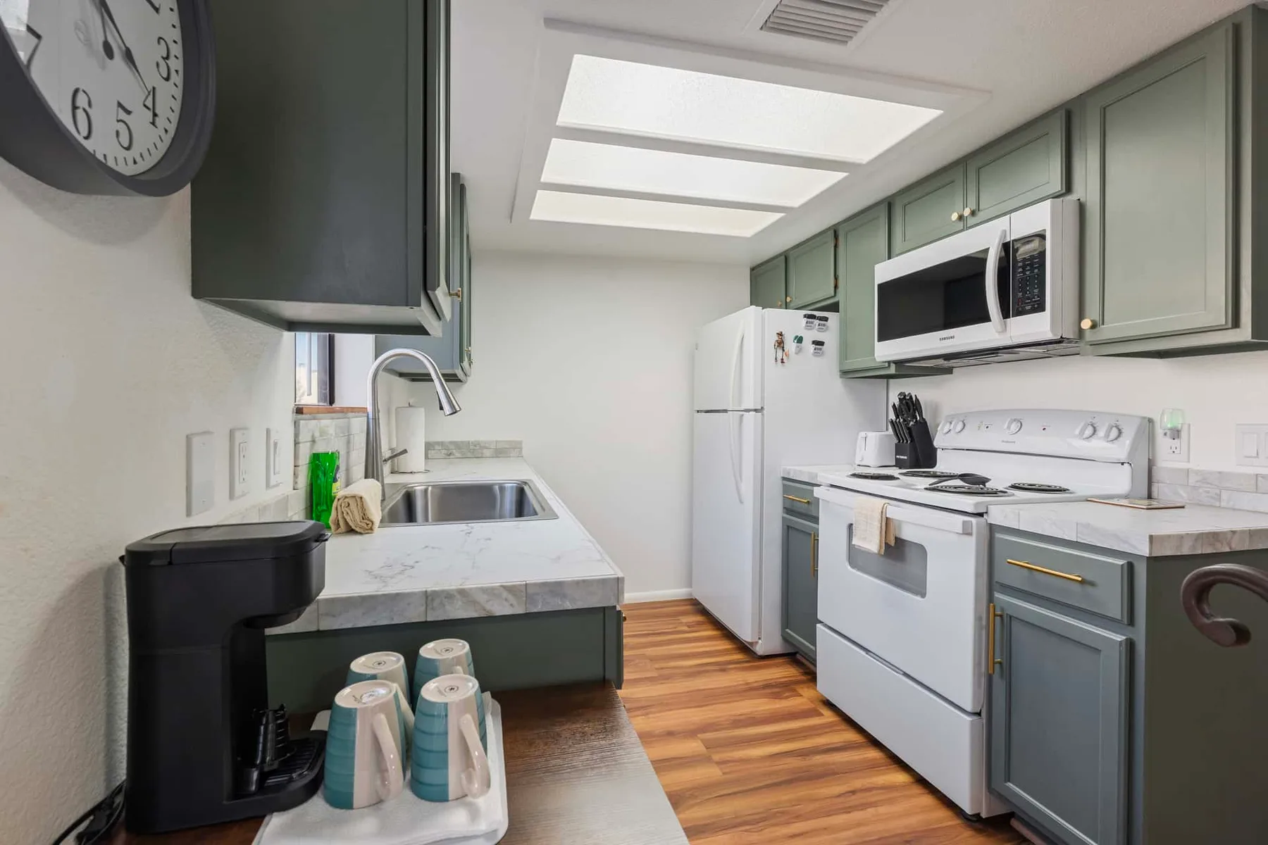 A compact kitchen with pale cabinetry, a refrigerator, and a range.