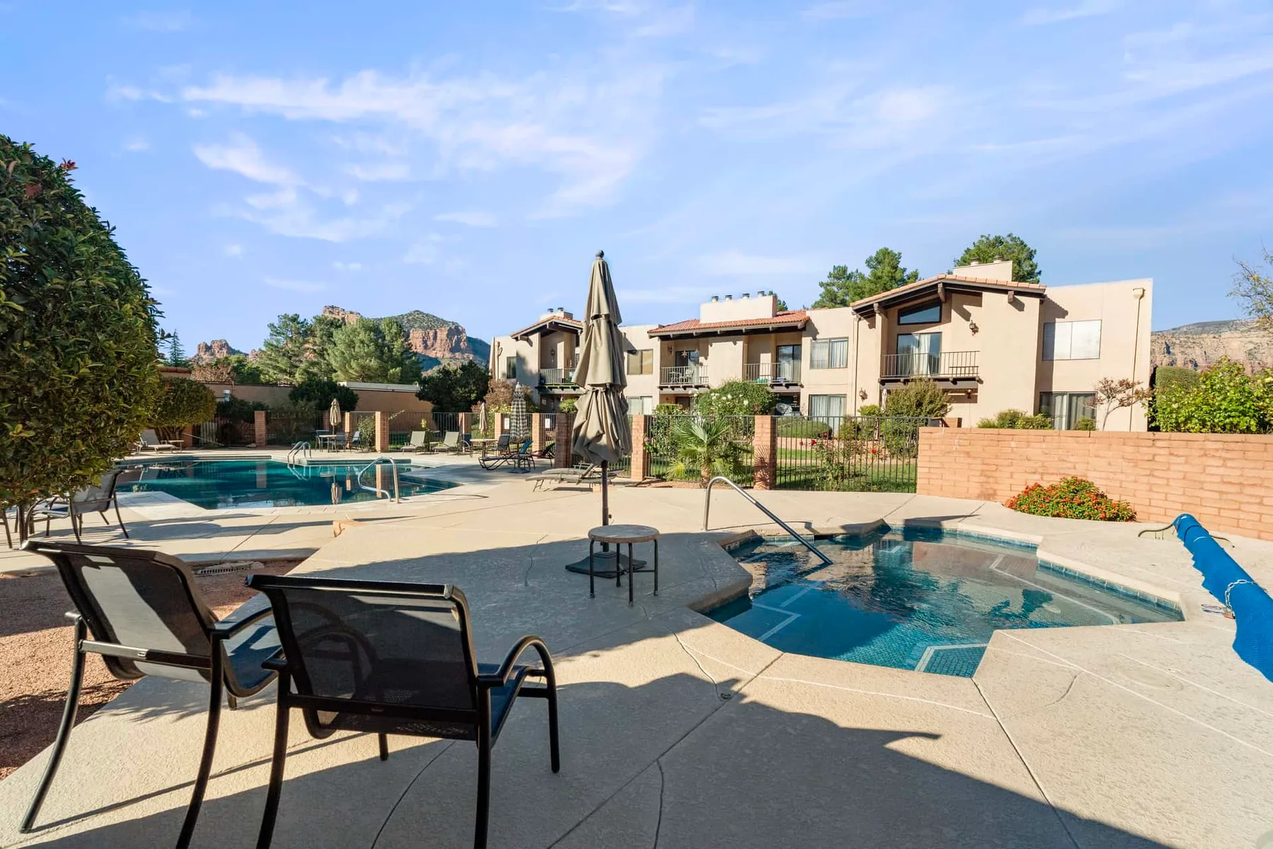 An outdoor pool area with seating and apartment buildings in the background.