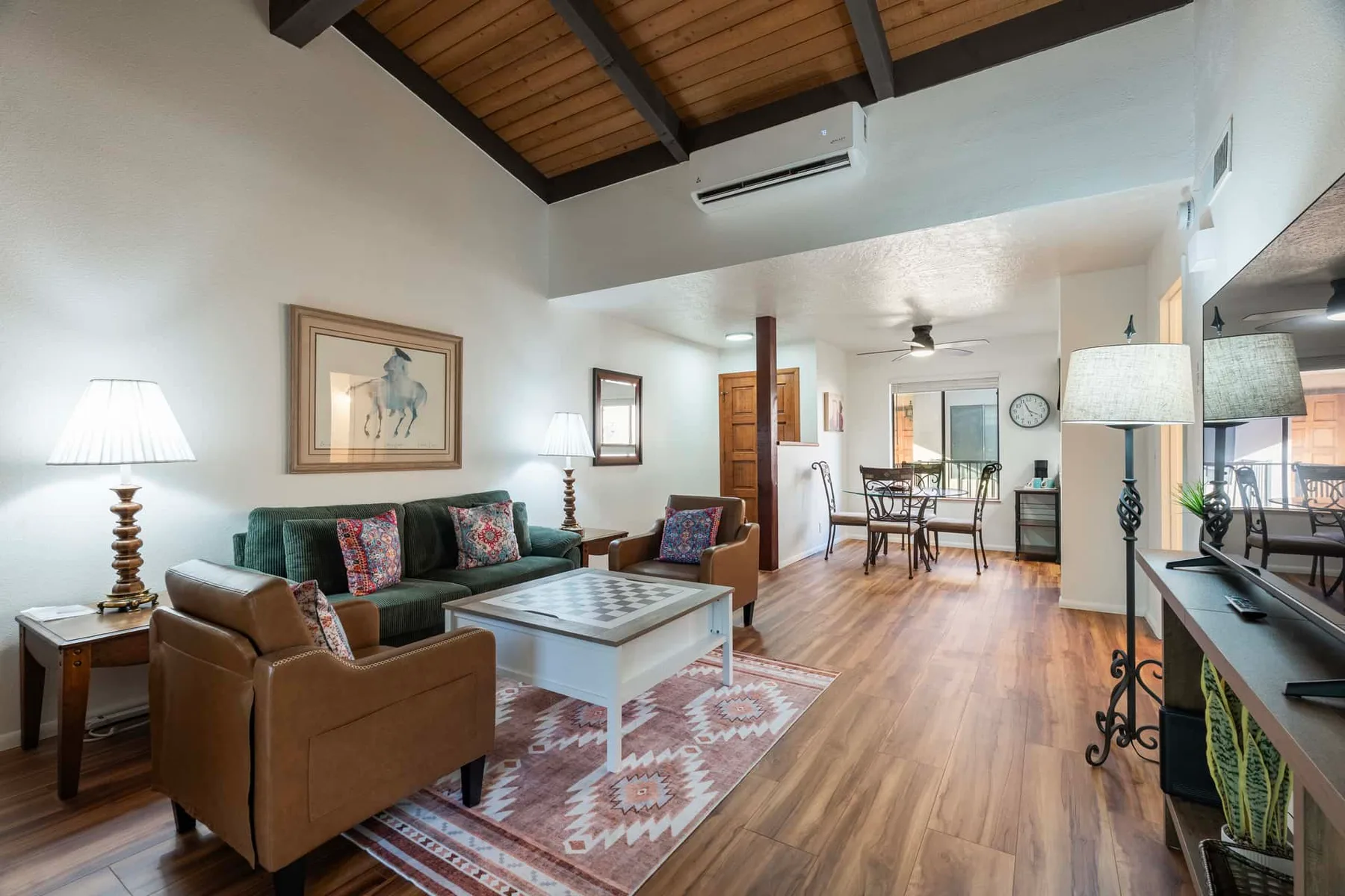 A living room with seating, a coffee table, and a dining area beyond.