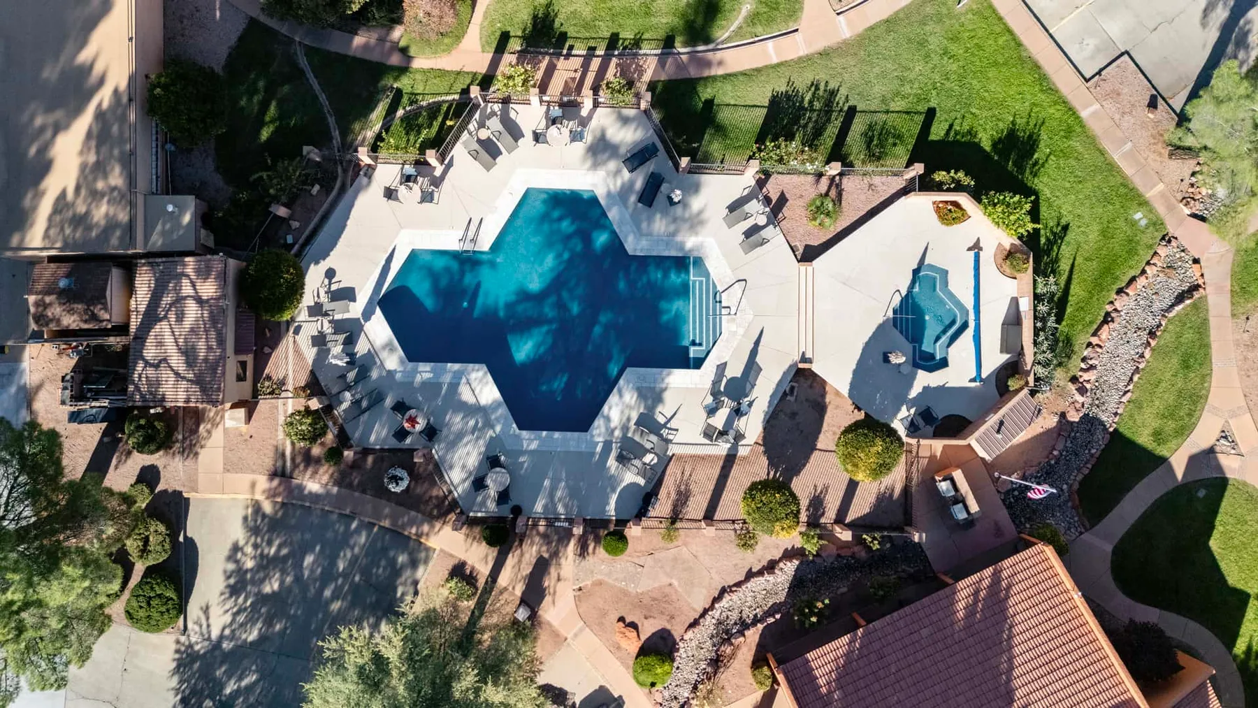 Una piscina al aire libre y un patio están rodeados de senderos y vegetación.