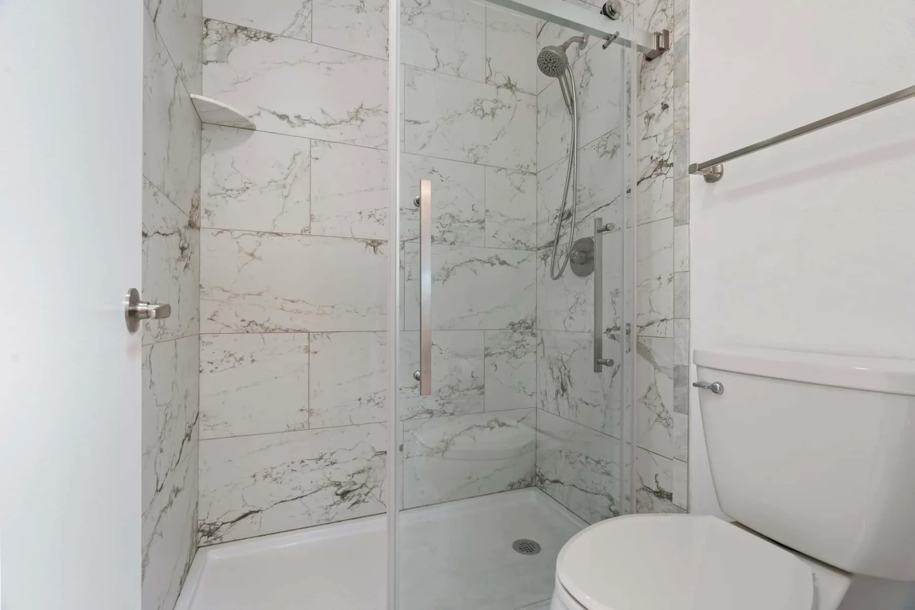 A tiled bathroom with a glass shower and toilet.