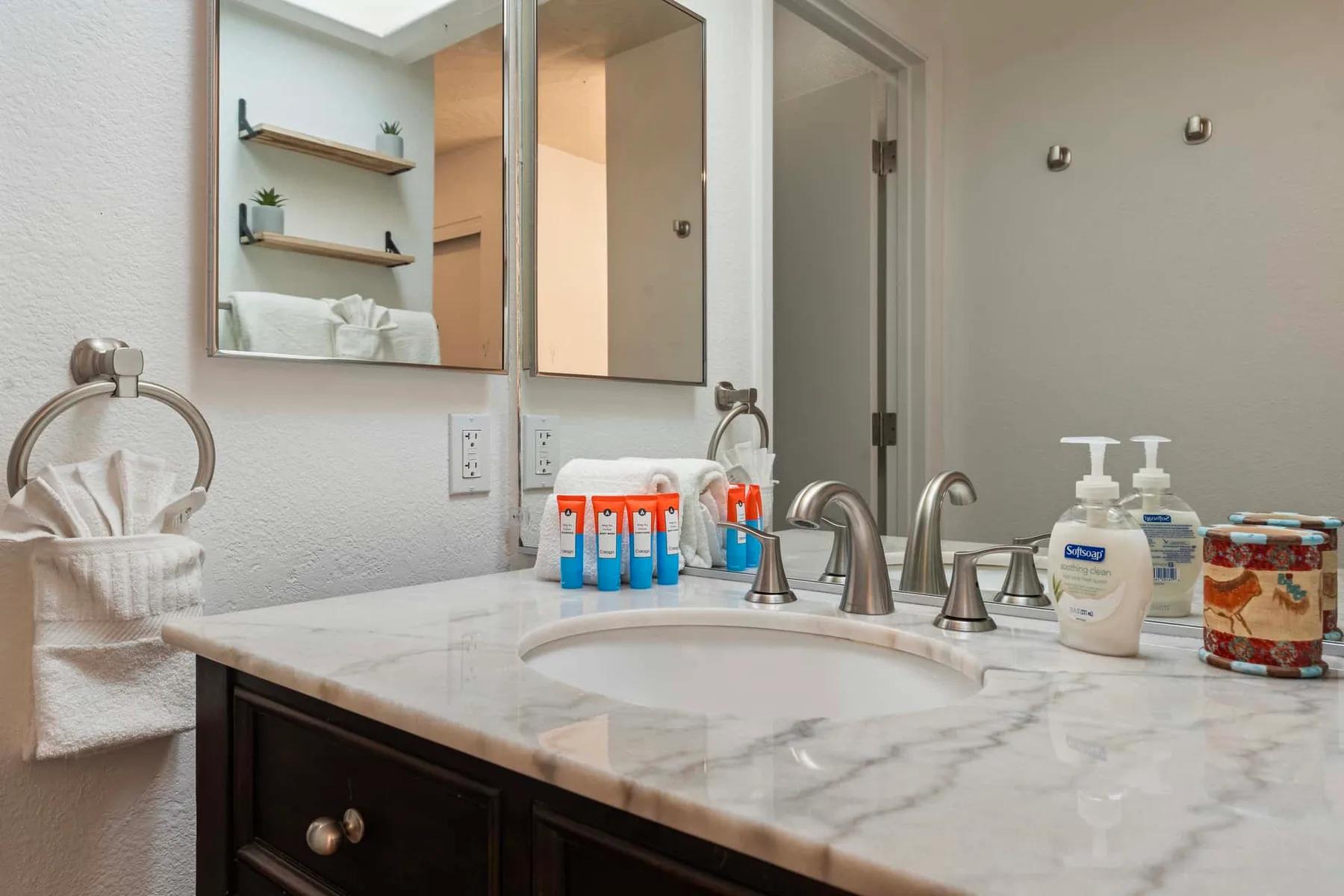 A bathroom vanity with a sink, mirror, and toiletries on the counter.