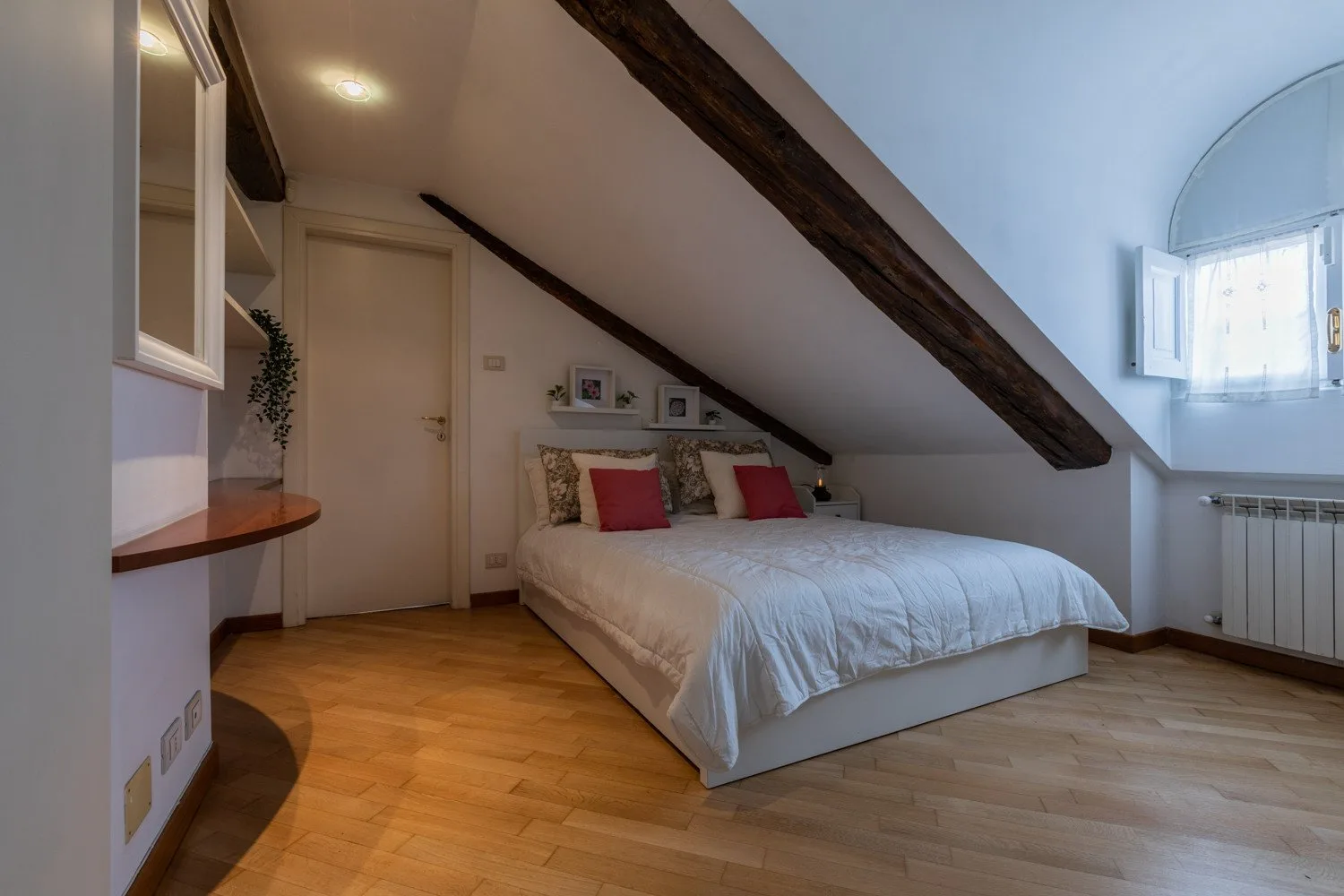 A bedroom with a bed beneath a sloped ceiling and a skylight.