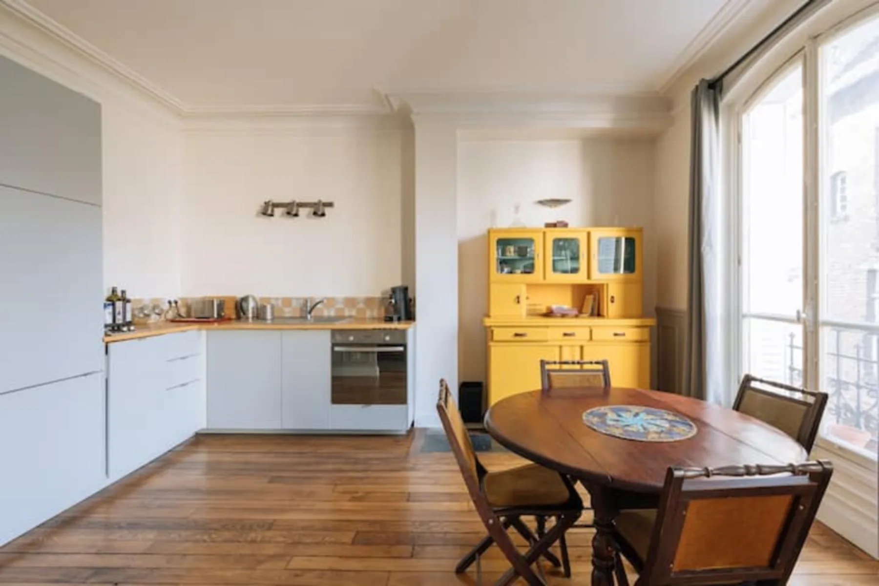A dining area with a wooden table beside a compact kitchen.