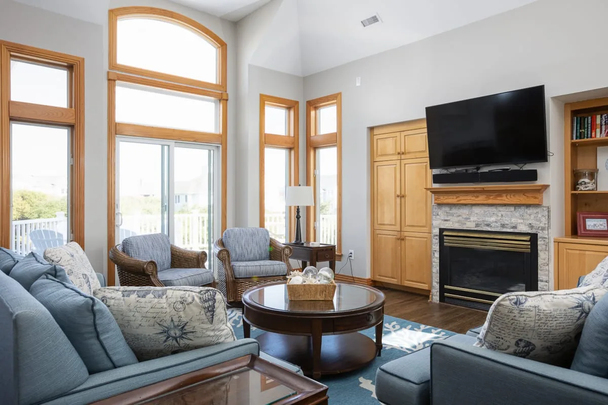 A bright living room with seating arranged around a coffee table and fireplace.