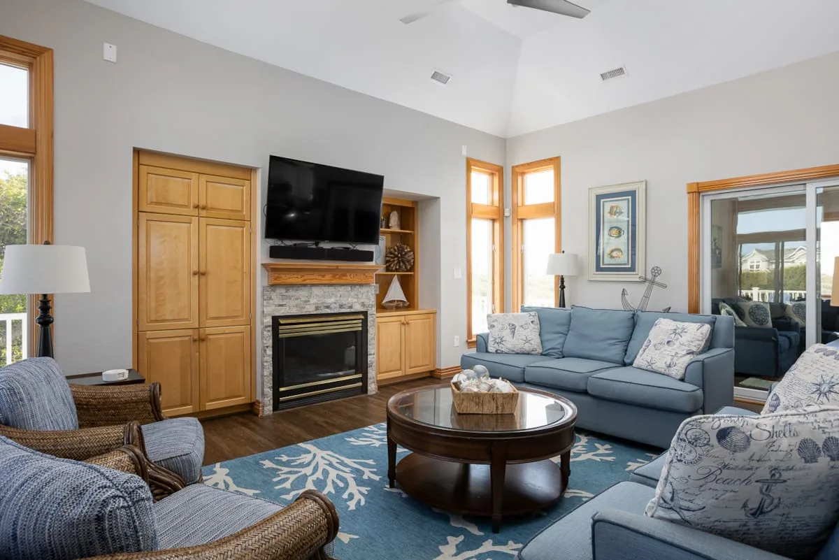 A living room with seating arranged around a coffee table and fireplace.