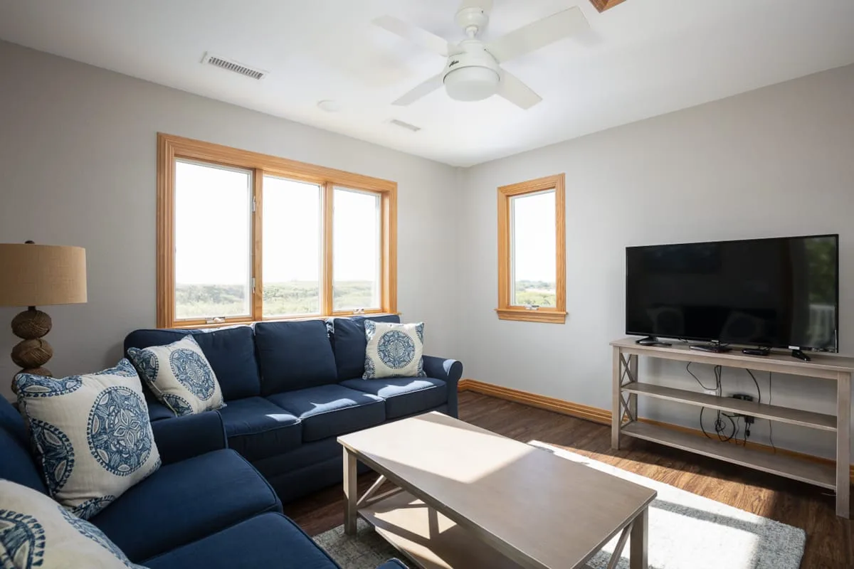 A living room with a navy sectional, coffee table, and large windows.