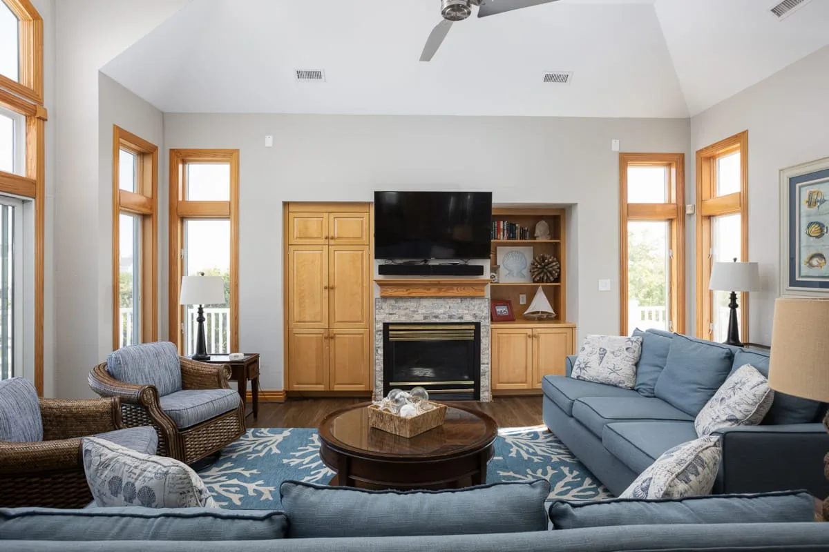 A bright living room with seating arranged around a coffee table and television.