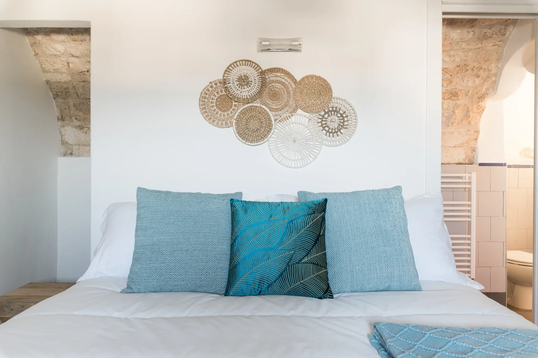 Un dormitorio con una cama bien tendida y arte decorativo en la pared.