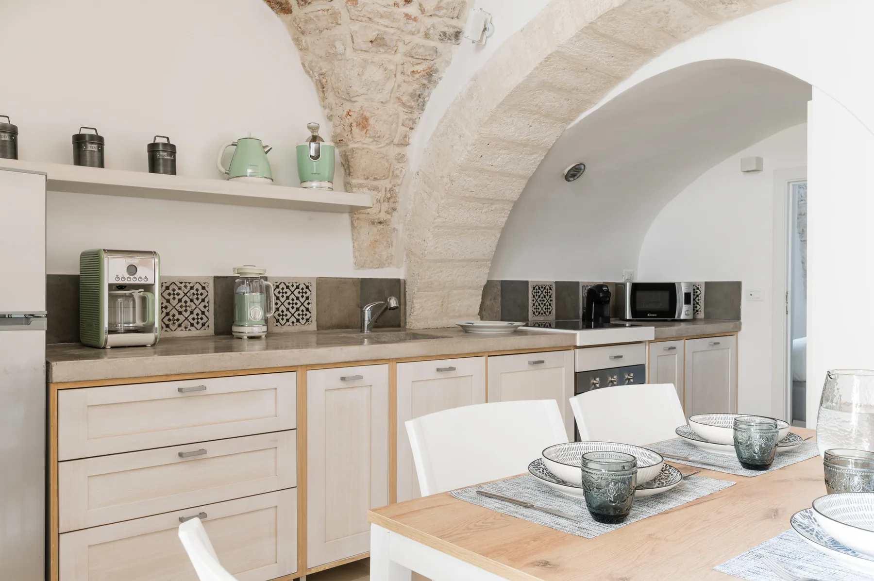 Una cocina luminosa con gabinetes claros, un salpicadero de azulejos y una mesa de comedor.