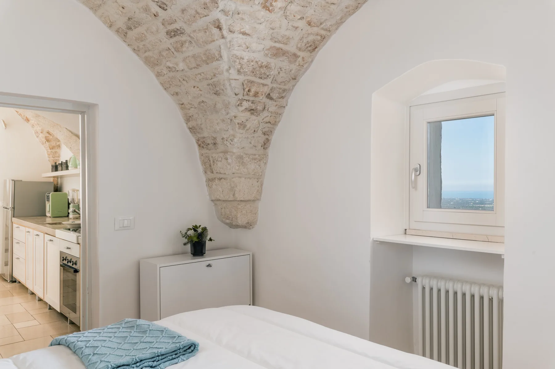 Un dormitorio con una cama bajo un techo abovedado de piedra y una ventana.