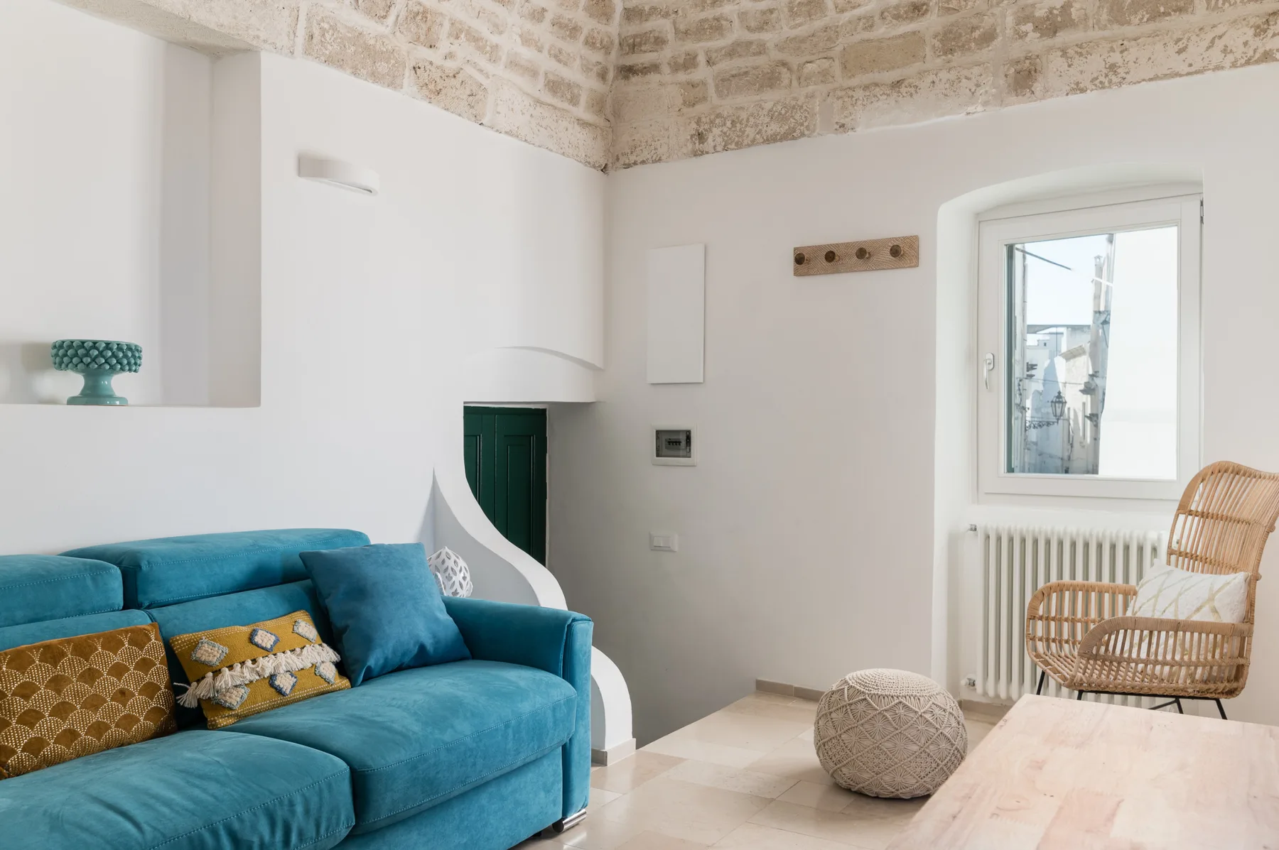 Una sala luminosa con asientos azules, una silla tejida y una mesa baja.
