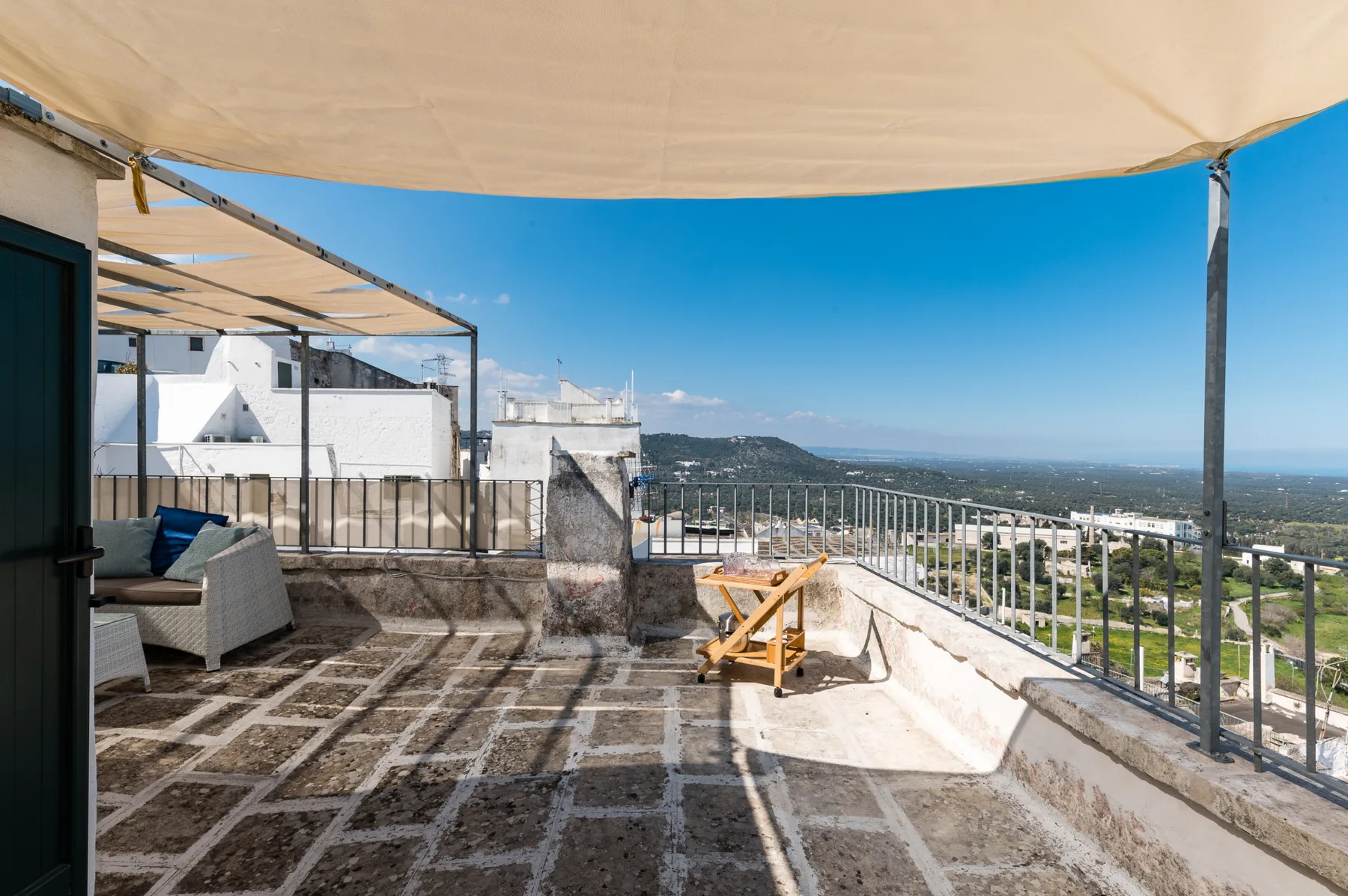 Una terraza soleada con asientos al aire libre y vistas al paisaje circundante.