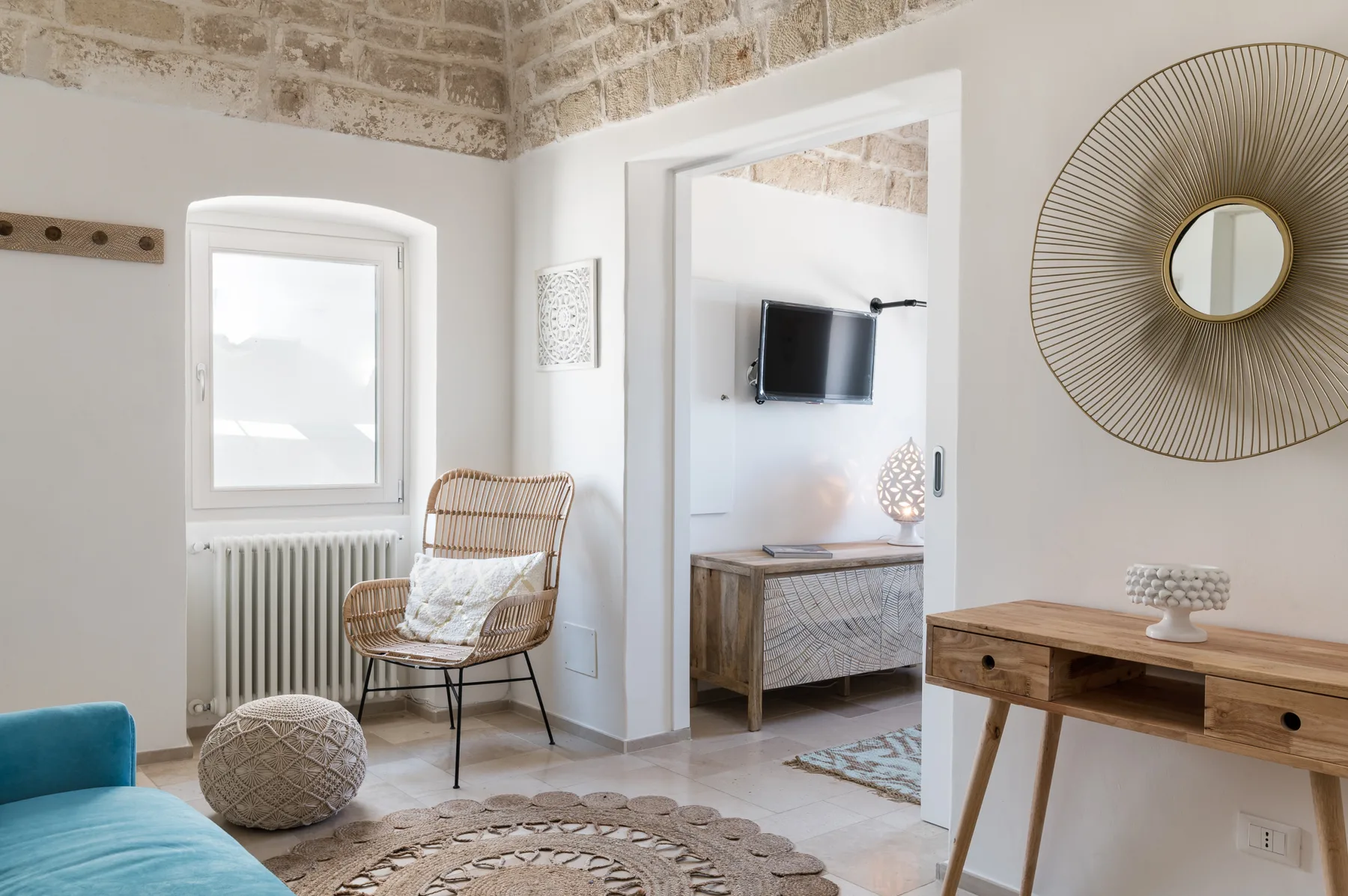 Una sala luminosa con una silla tejida junto a una ventana.