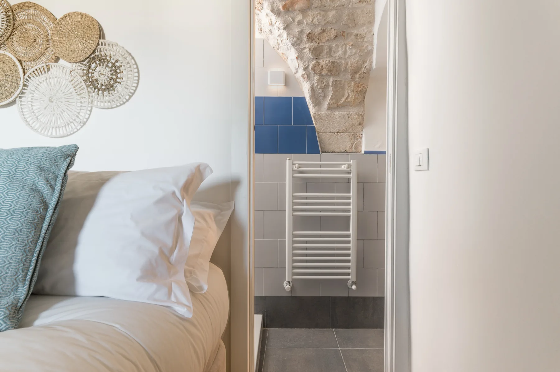 Un dormitorio junto a un baño alicatado con un radiador toallero de pared.