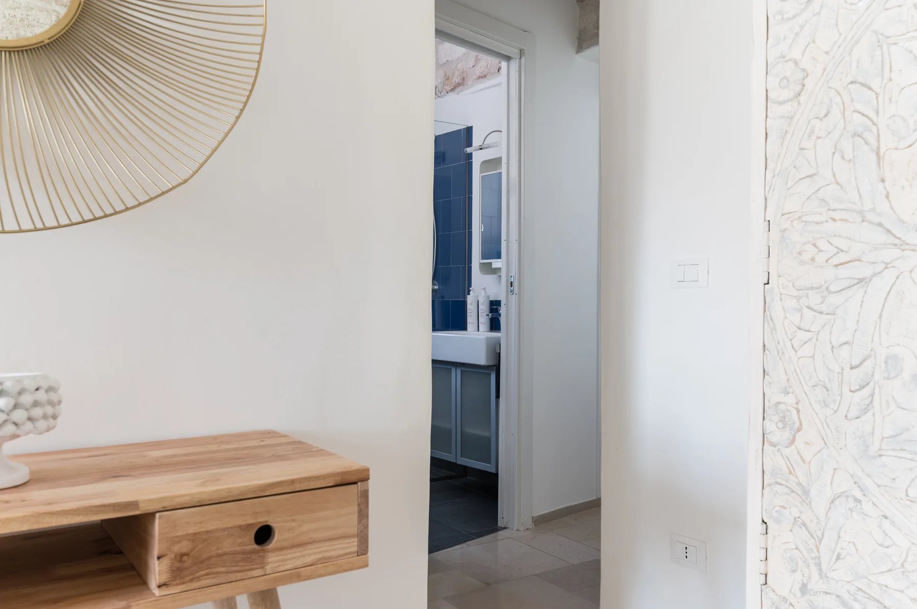 Un pasillo da a un baño, con una mesa consola de madera en primer plano.