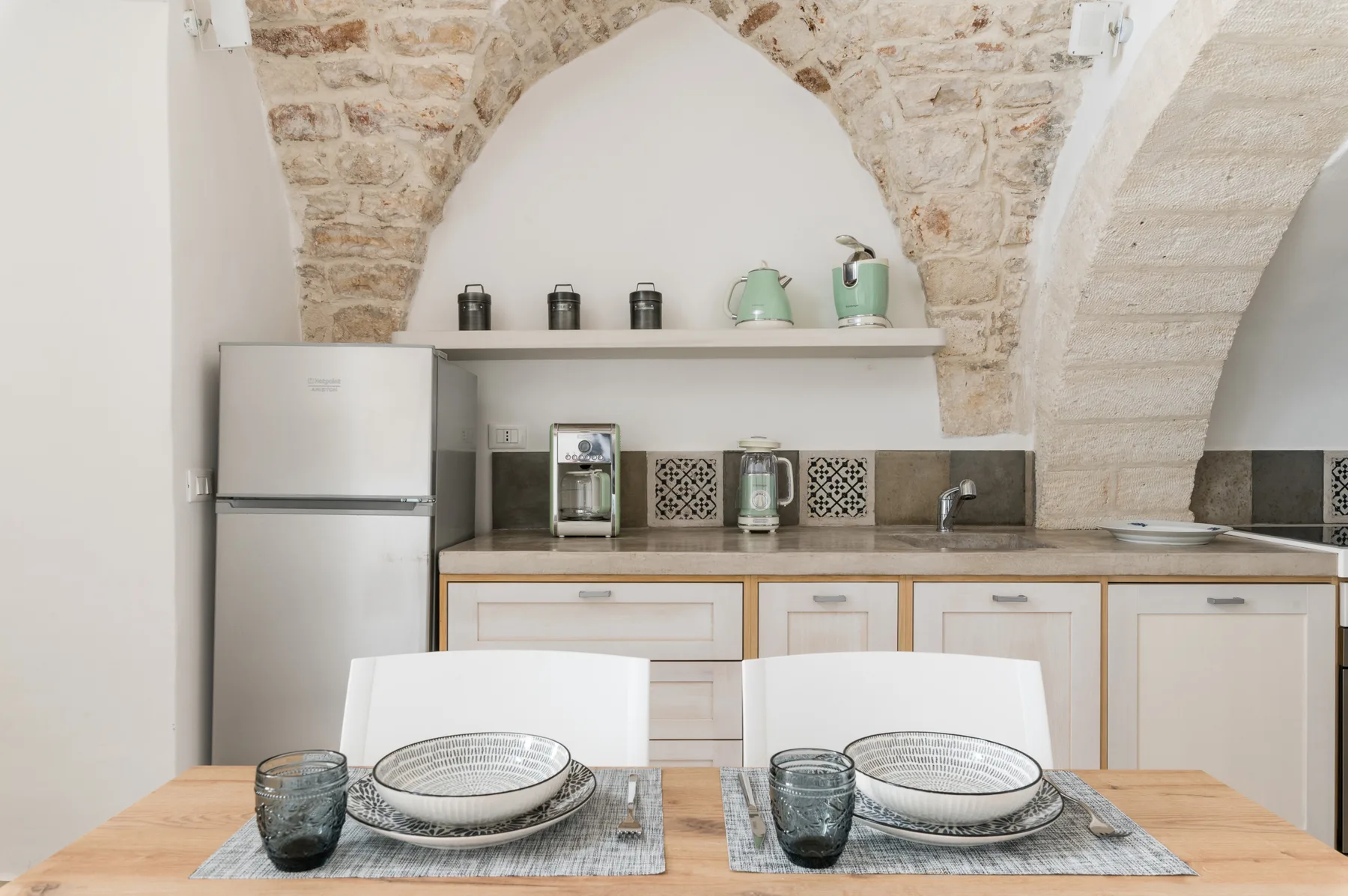 Una mesa puesta frente a una cocina compacta con refrigerador y encimera.