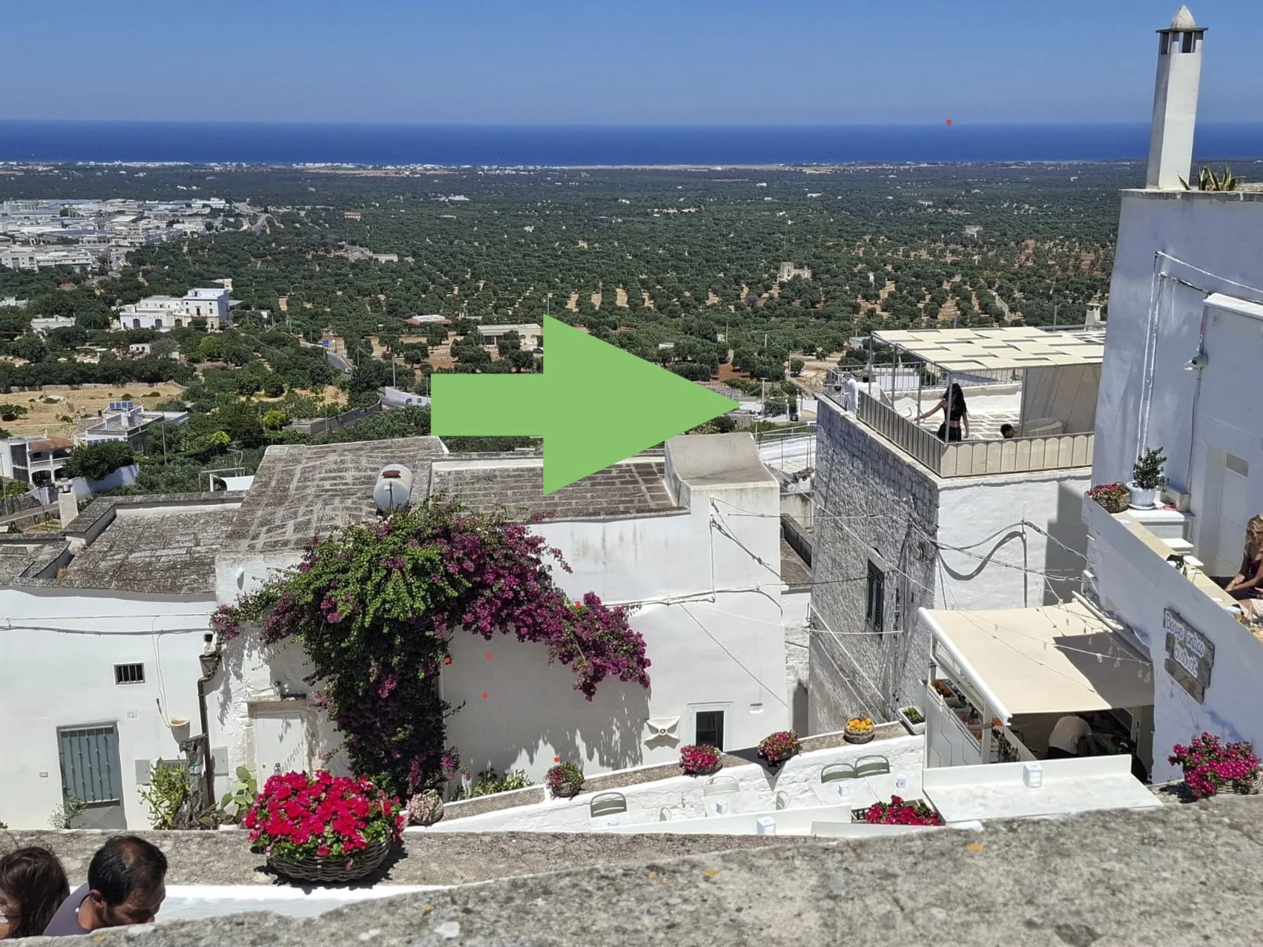 Una terraza en la azotea ofrece vistas de edificios blancos, el campo verde y el mar.