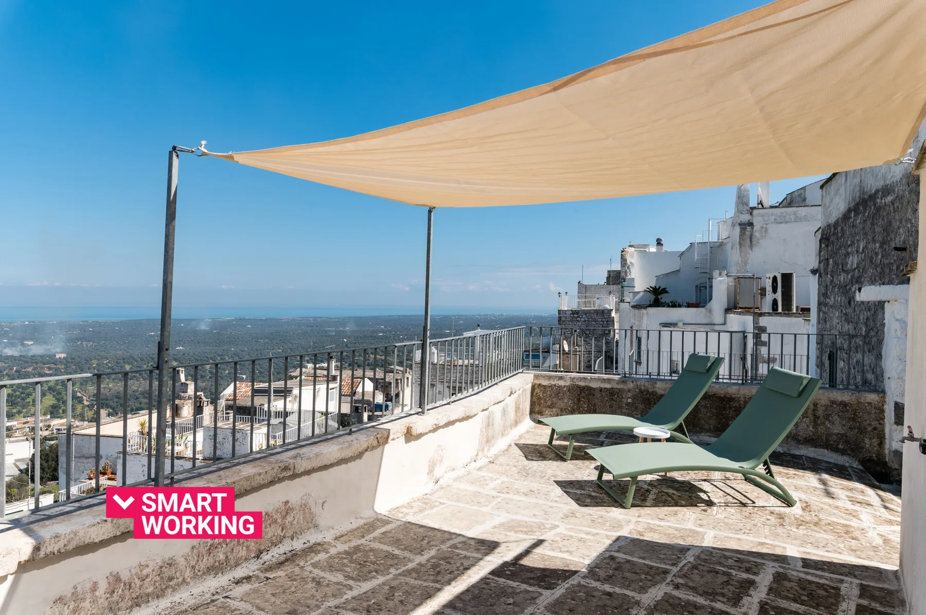 Una terraza soleada en la azotea tiene asientos de descanso bajo un toldo.