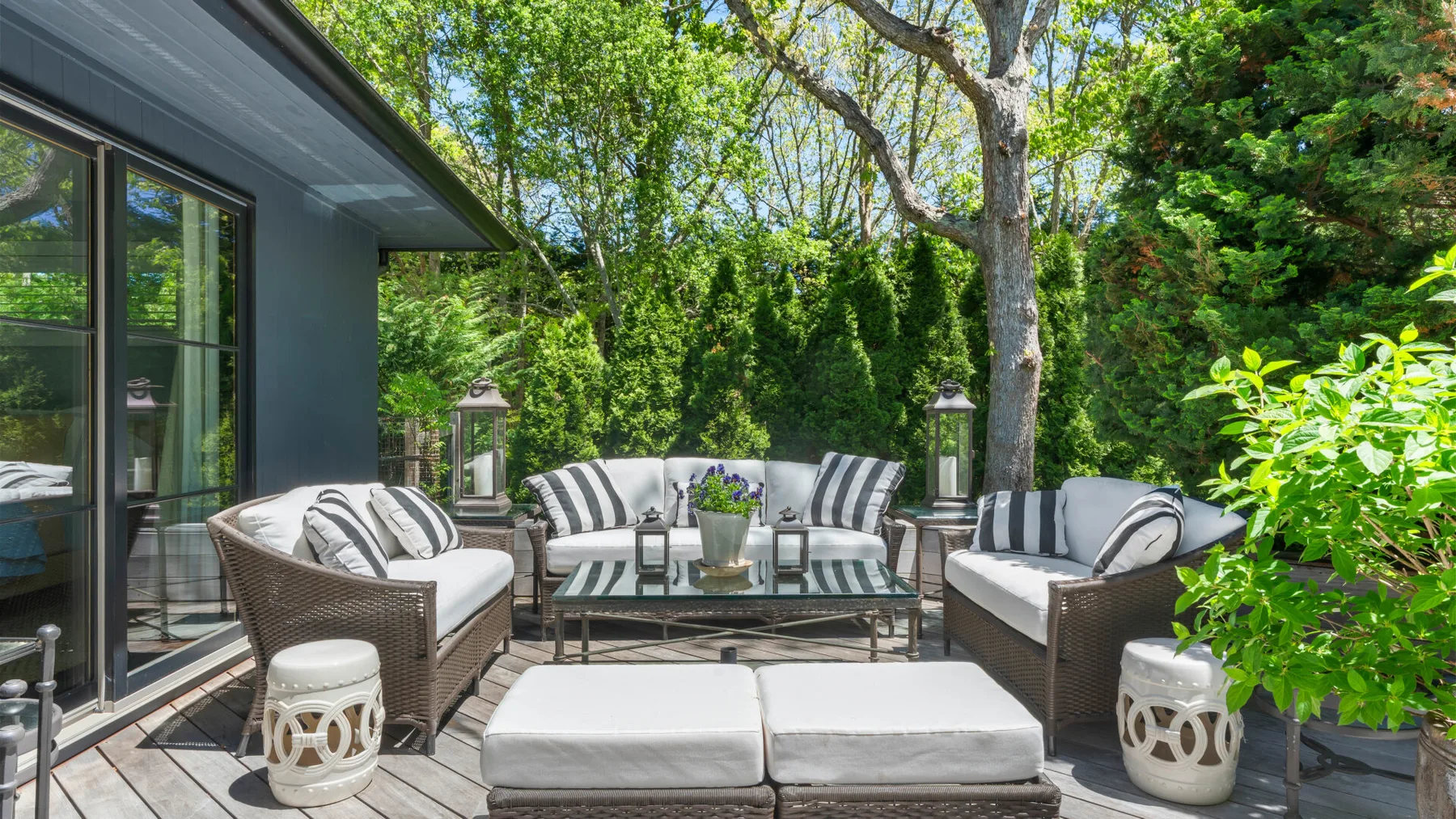An outdoor seating area with cushioned furniture and a glass-topped table.