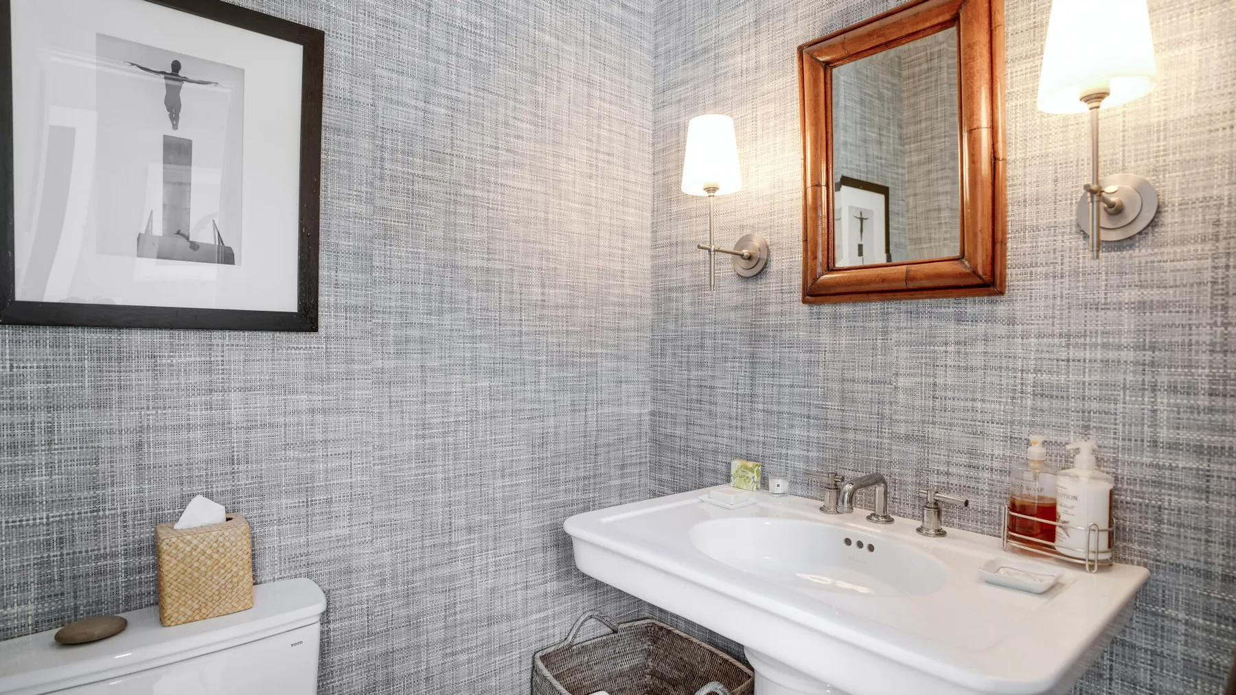 A bathroom vanity with a sink, wall mirror, and framed artwork.