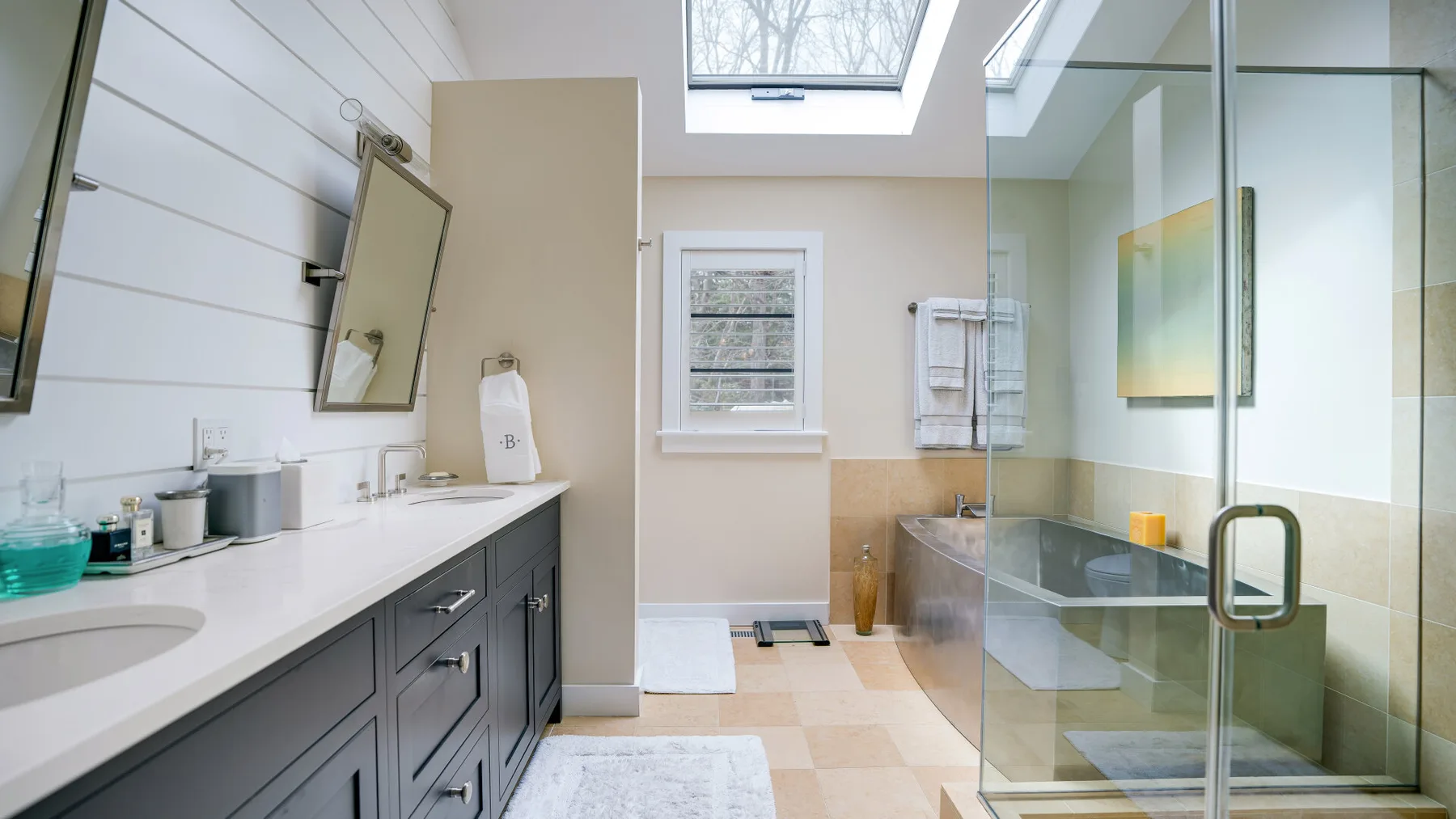 A bright bathroom with a long vanity and glass shower.