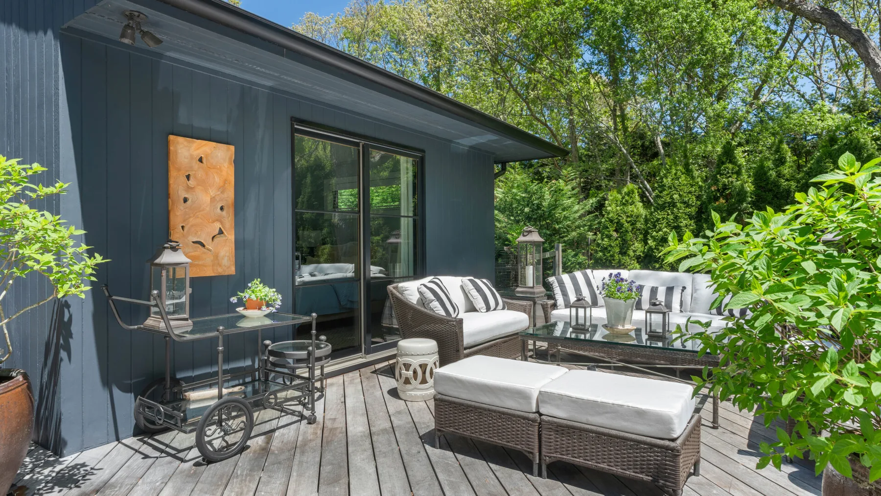 An outdoor deck with seating and a low table beside a dark-sided building.