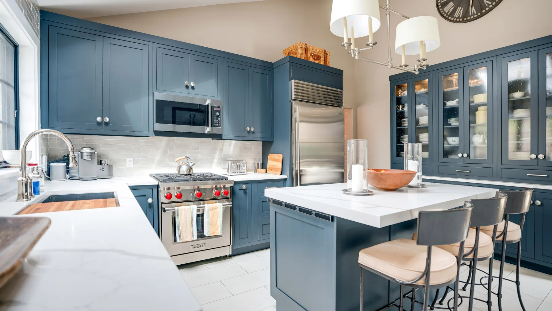 A spacious kitchen with blue cabinets, a central island, and stainless steel appliances.