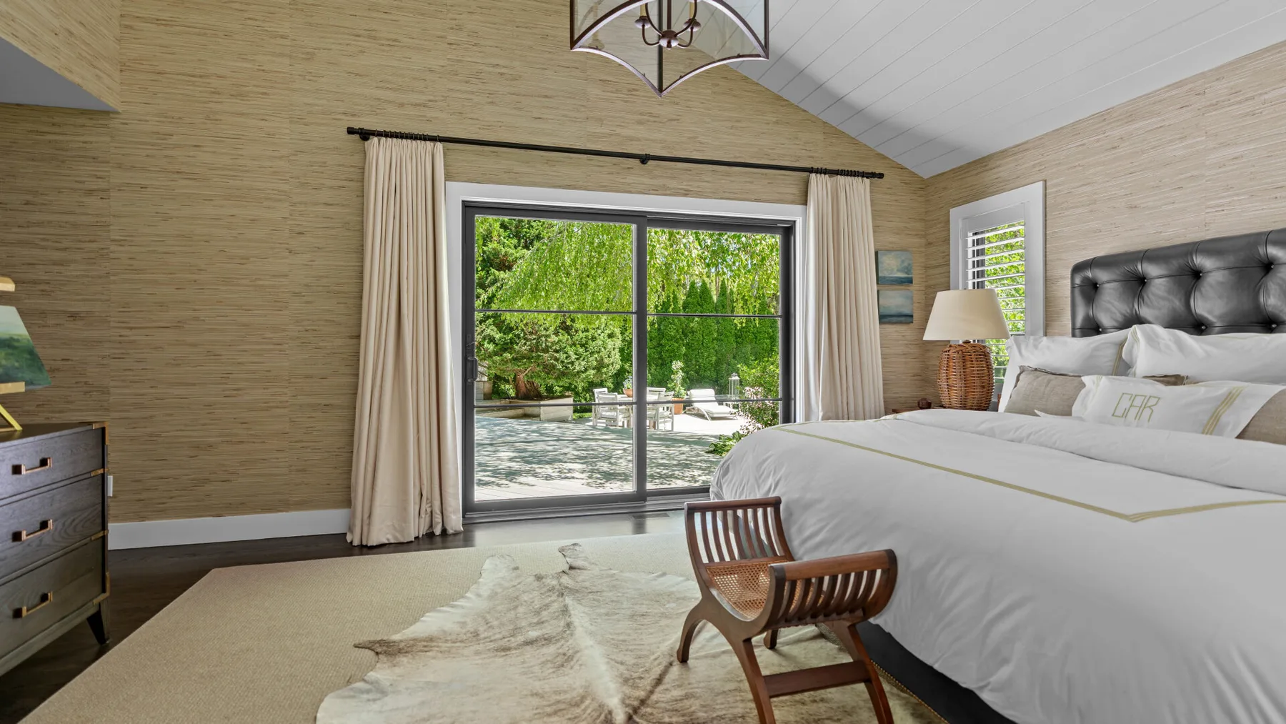 A bright bedroom with a large bed and sliding glass doors opening onto a garden.