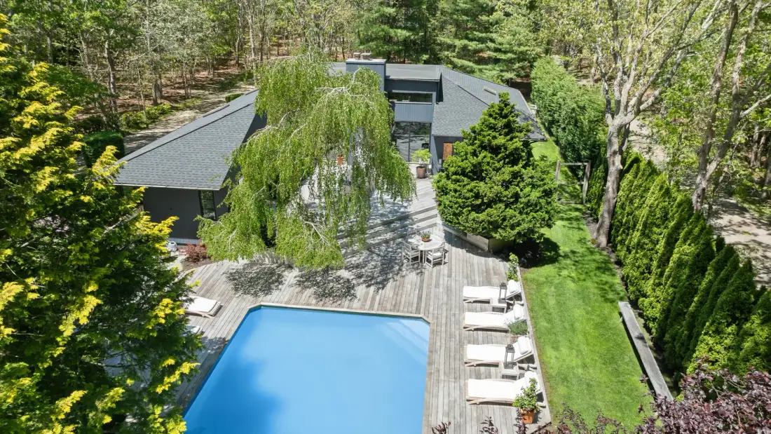 Aerial view of a swimming pool beside a wooden deck and landscaped garden.