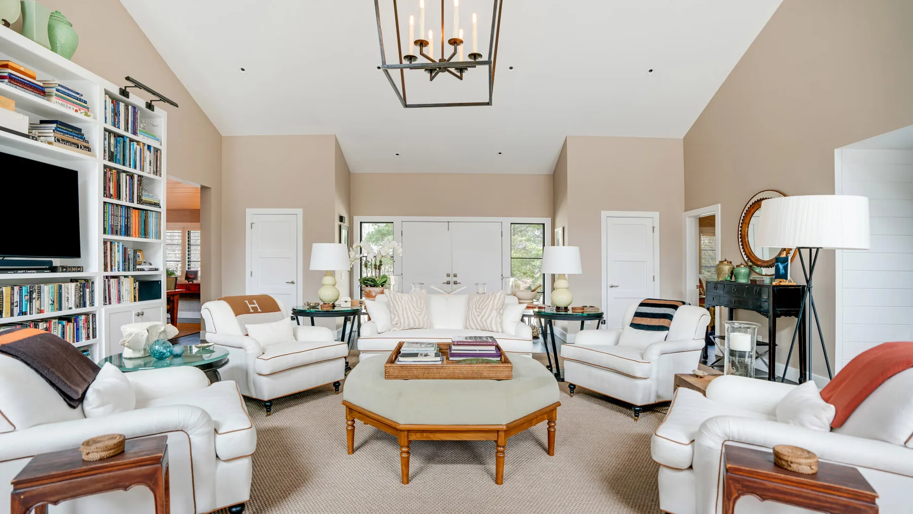 A spacious living room with white seating arranged around a wooden coffee table.