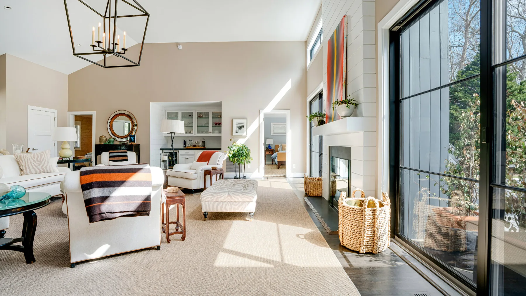 A bright living room with seating, a coffee table, and large windows.
