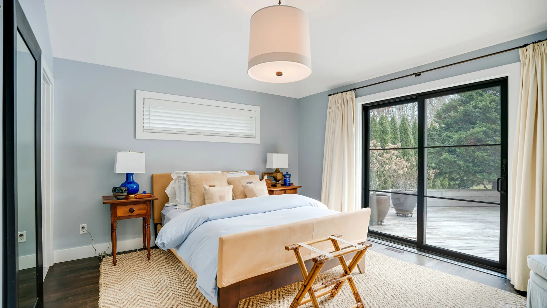 A bedroom with a bed, bedside tables, and sliding glass doors opening onto a patio.