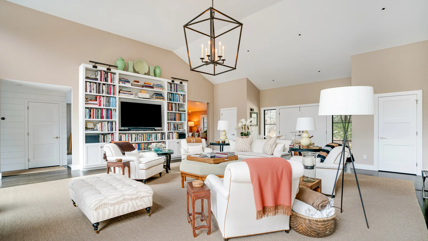 A bright living room with seating, a built-in bookcase, and a large television.