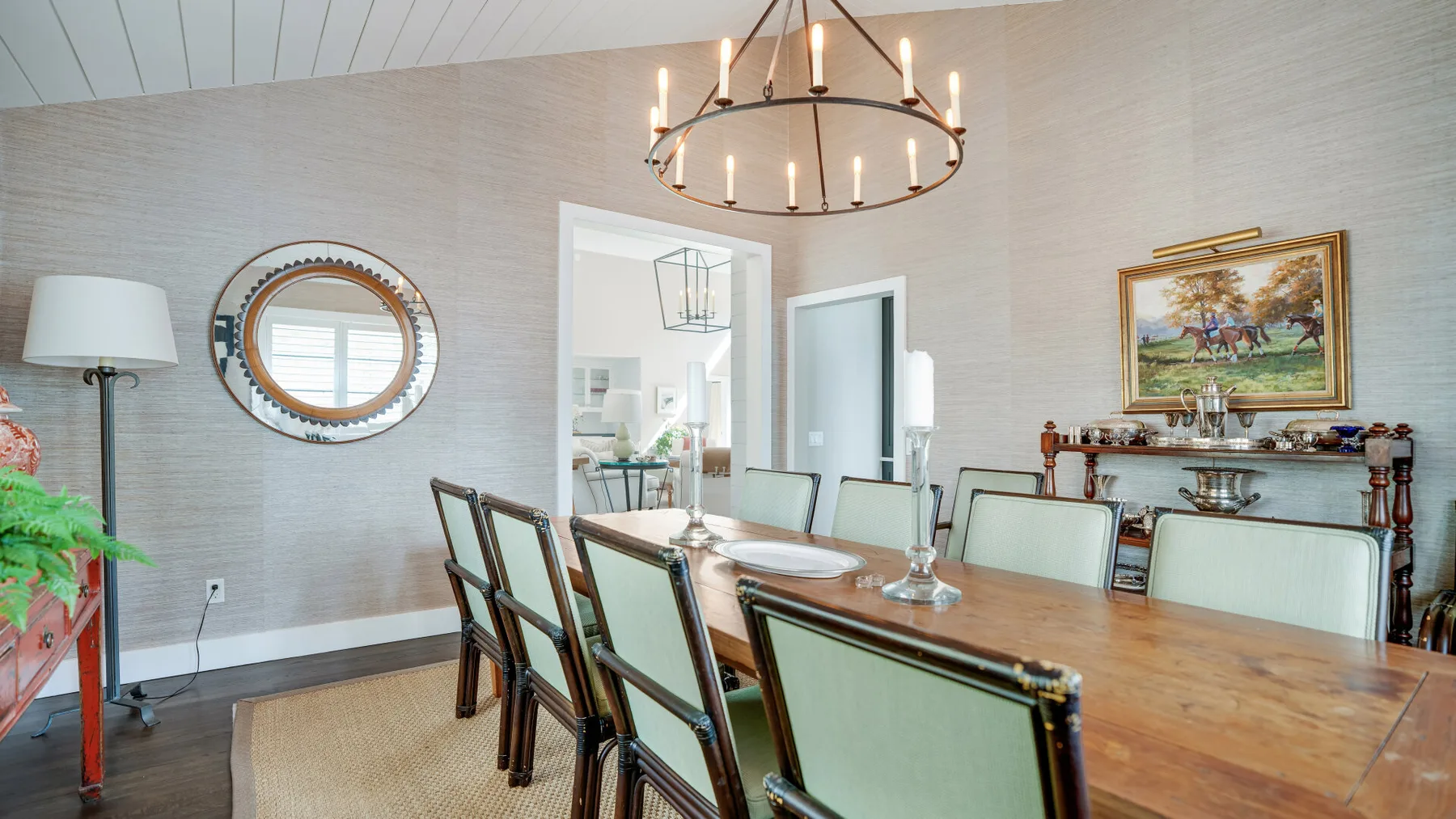 A dining room with a long wooden table and chairs beneath a circular chandelier.