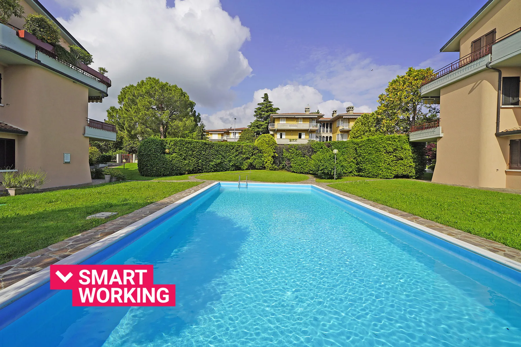 A swimming pool sits in a landscaped courtyard between residential buildings.