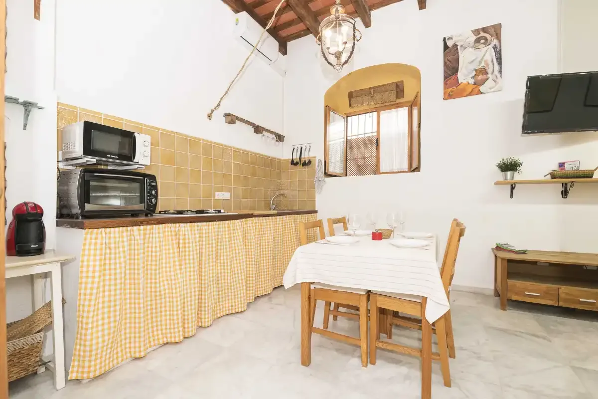 A dining area with a table, chairs, and a long checked tablecloth.