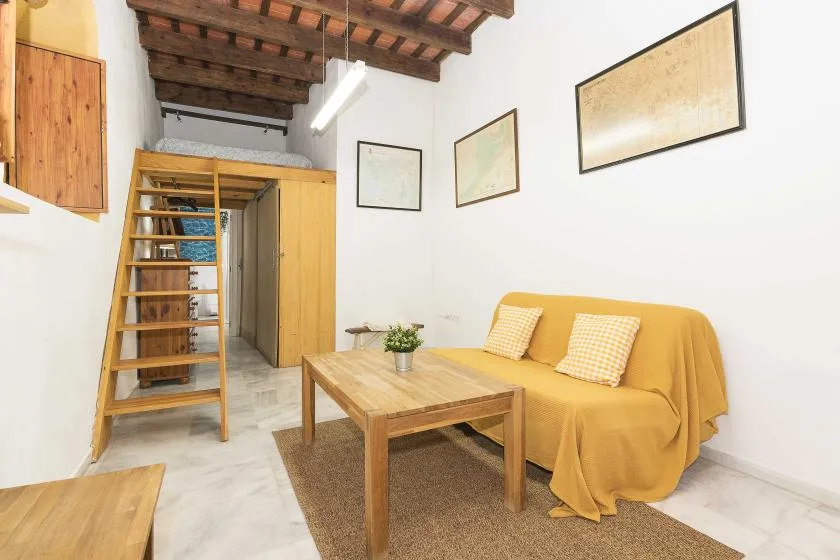 A bright living area with yellow seating, a wooden coffee table, and exposed ceiling beams.