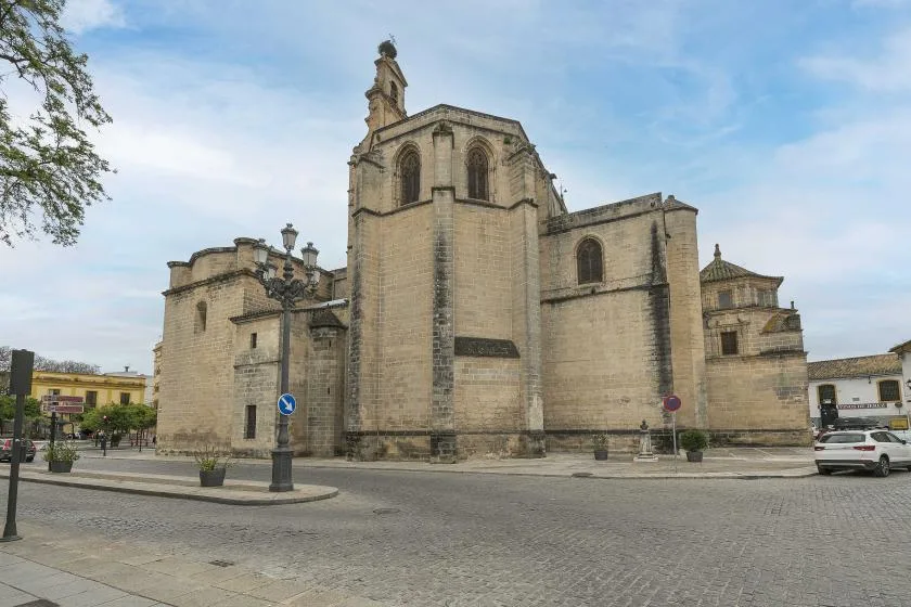 A large stone church stands beside a paved town square under a blue sky.