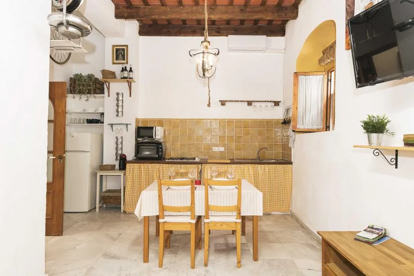 A kitchen and dining area with a table and wooden ceiling beams.