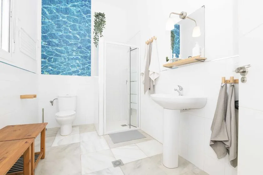 A bright bathroom with a shower, sink, and toilet.