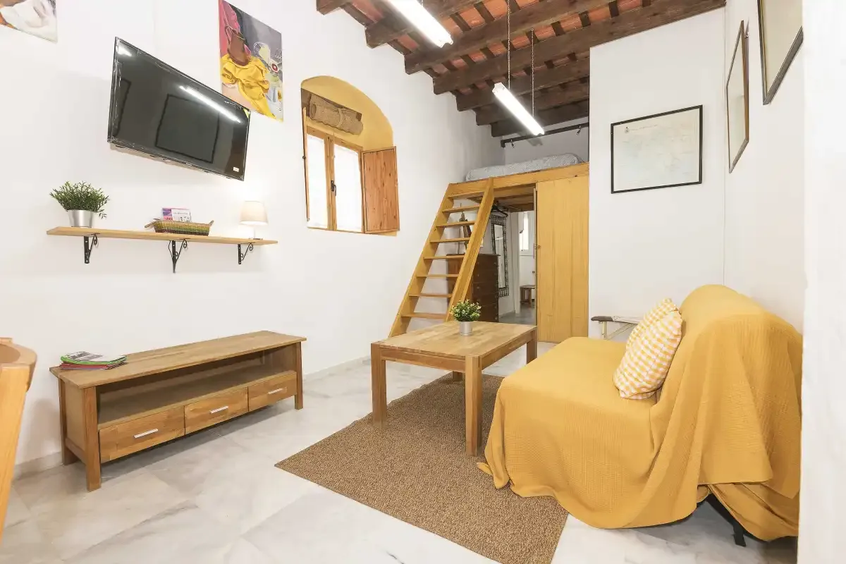 A bright loft living area with seating, a coffee table, and a wall-mounted television.