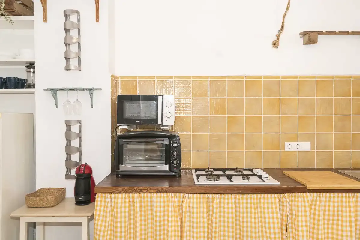 A compact kitchen with a microwave and cooktop along a tiled wall.