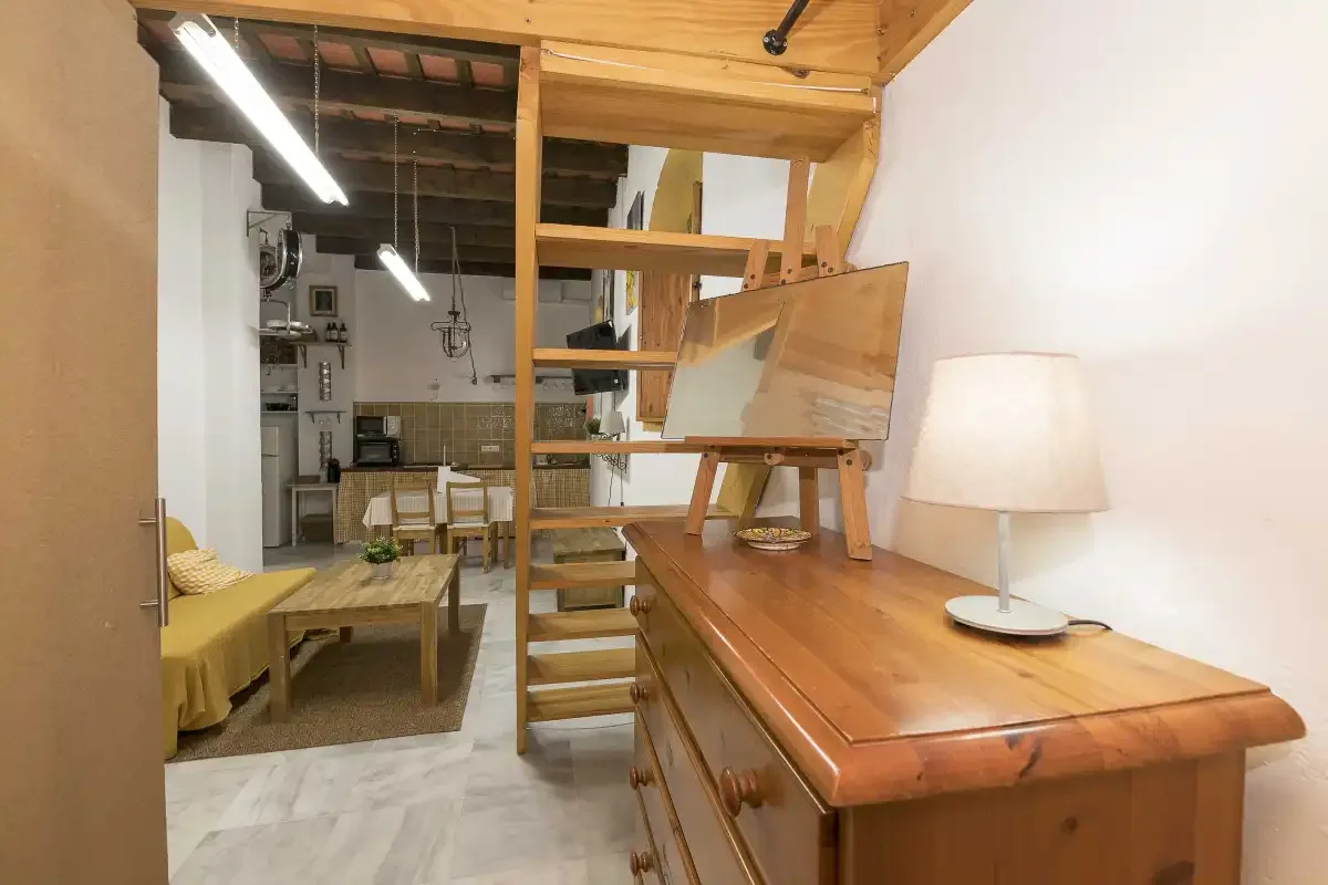 A loft interior with a wooden staircase beside a long wooden table.